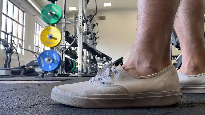 Used White Vans on Feet in a Gym